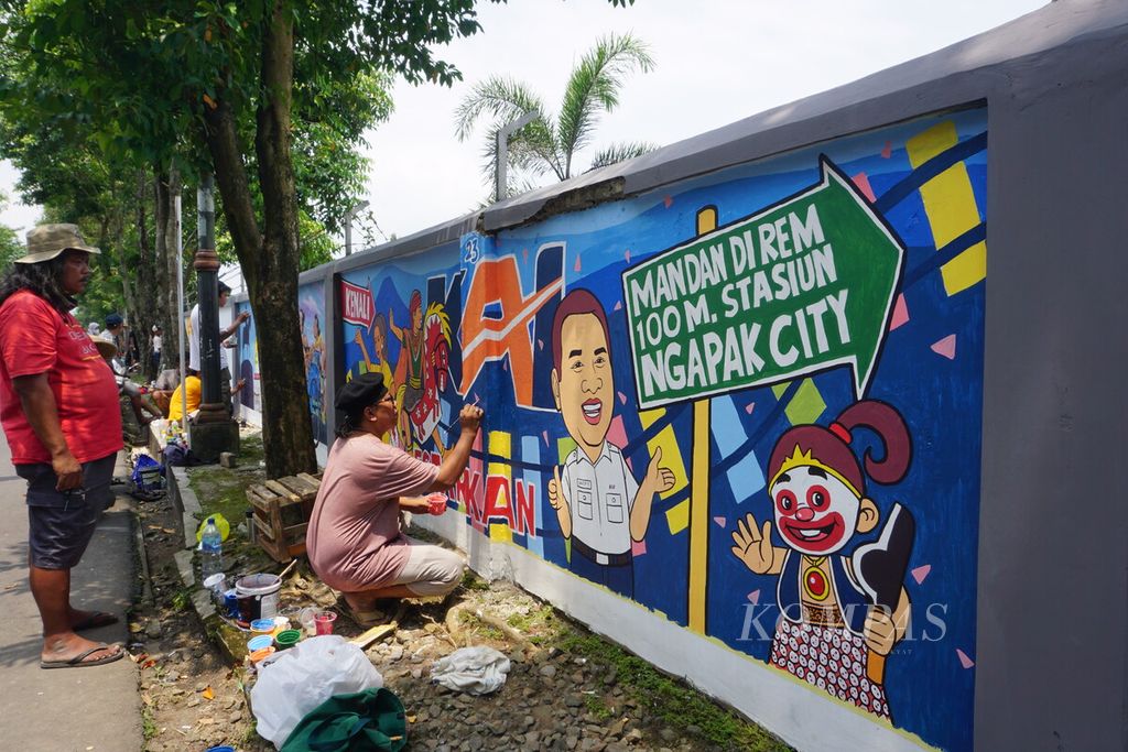 Para seniman mural sedang menyelesaikan lukisan aneka ikon khas Banyumas di tembok dinding area Stasiun Purwokerto, Banyumas, Jawa Tengah, Selasa (29/3/2022).