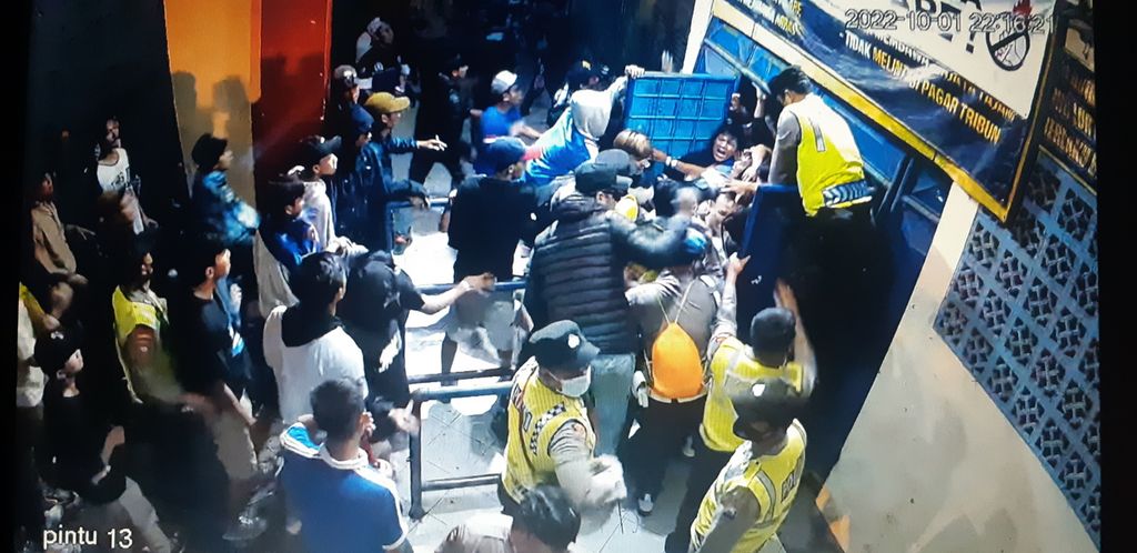 Rekaman video CCTV Stadion Kanjuruhan, Kabupaten Malang, Jawa Timur saat tragedi yang menewaskan 135 orang Sabtu (1/10/2022). Beberapa petugas kepolisian sempat membantu pintu 13 yang macet oleh sesaknya penonton yang panik hendak keluar. Upaya membuka pintu geser gagal.