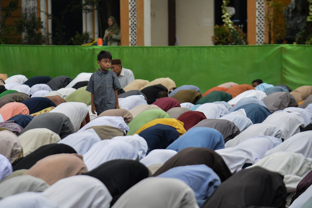 A child plays amidst worshipers performing Eid al-Fitr prayer at the SMK TU Muhammadiyah Cikampek field, Karawang, West Java, on Friday (21/4/2023).