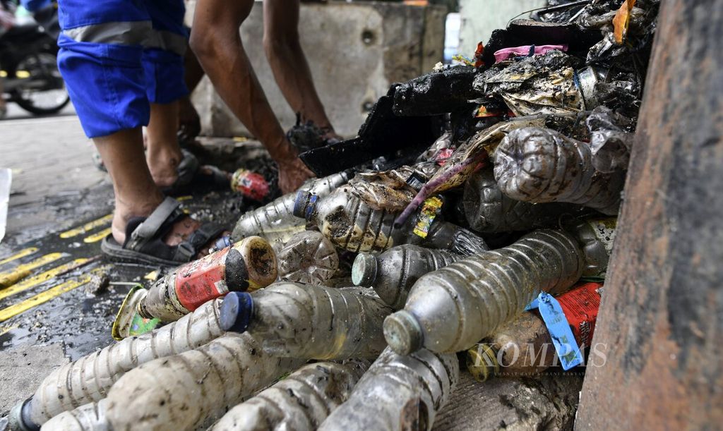 Petugas suku dinas sumber daya air membersihkan saluran air yang dipenuhi sampah, terutama botol-botol plastik, di kawasan Tanjung Duren, Jakarta Barat, Selasa (11/1/2022). 
