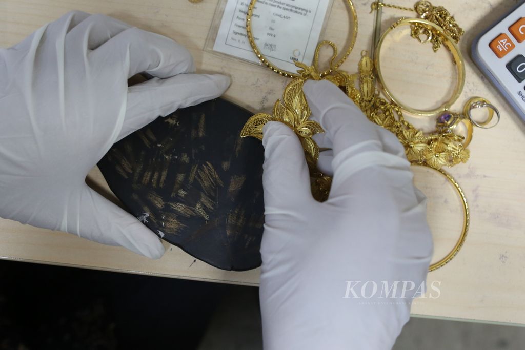 Pegawai Kantor Cabang Pegadaian Syariah di Jalan Kramat Raya, Jakarta, menggosok perhiasan emas warga yang digadai, dalam proses untuk mengetahui kadarnya, Rabu (29/7/2020).