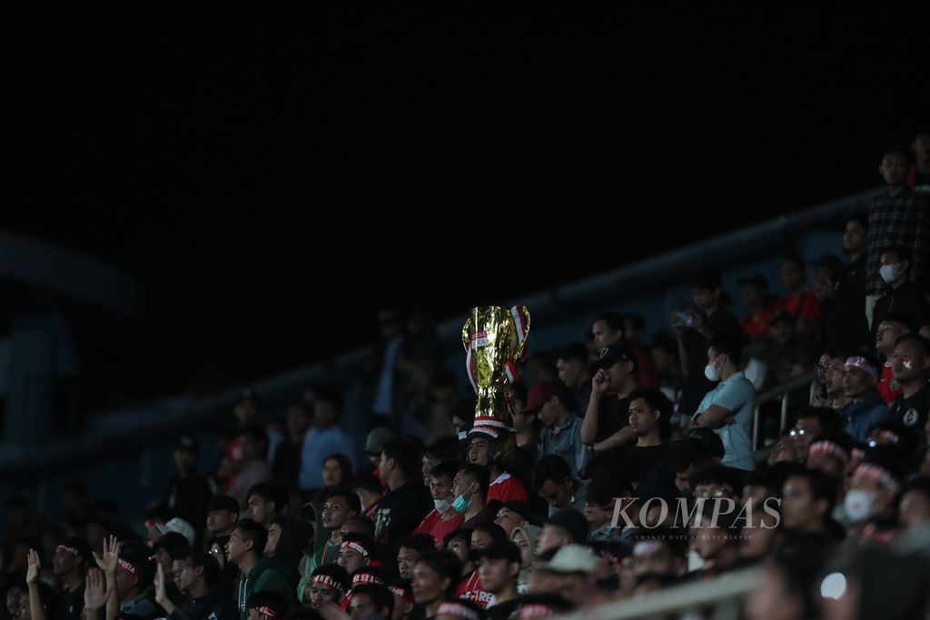 Seorang penonton mengenakan hiasan kepala berbentuk piala saat pertandingan semifinal Piala AFF U-16 antara Indonesia melawan Myanmar di Stadion Maguwoharjo, Sleman, DI Yogyakarta, Rabu (10/8/2022). 