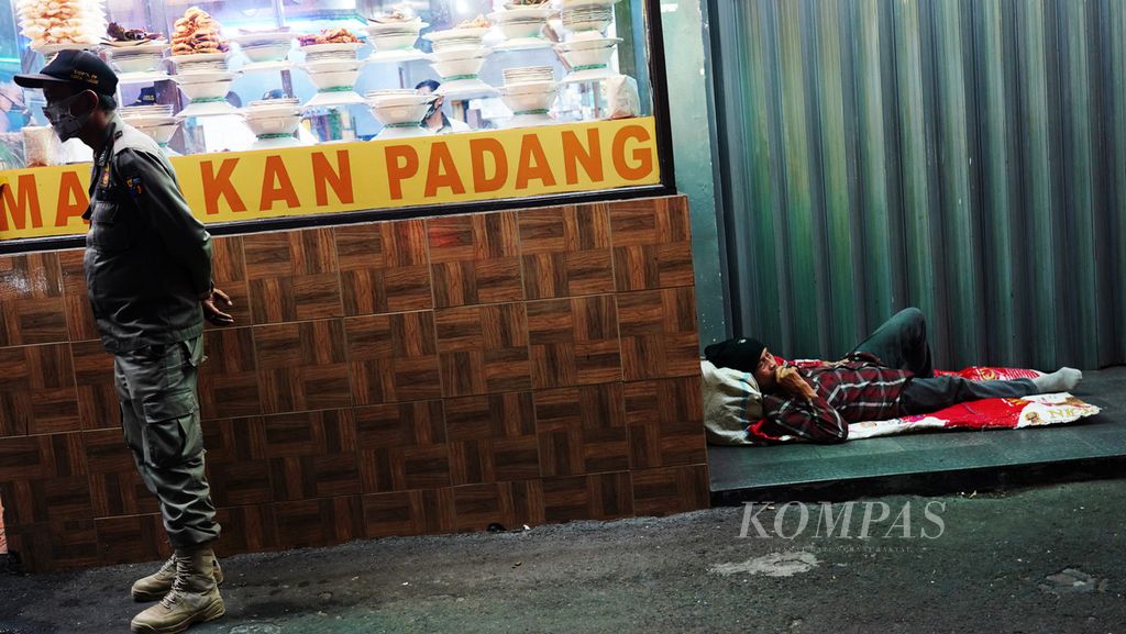 Seorang tunawisma tidur di depan pertokoan yang sudah tutup saat polisi pamong praja mengimbau salah satu warung makan di Jalan Jenderal Sudirman, Kota Bogor, Jawa Barat, yang masih buka saat jam malam berlaku, Minggu (30/8/2020). 