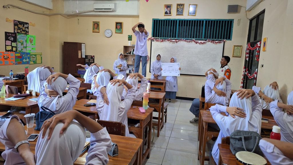 Siswa memperagakan gerakan melindungi kepala dan leher saat terjadi gempa bumi dalam simulasi gempa bumi di SMA Muhammadiyah 4, Jakarta Timur, Jumat (20/9/2024).