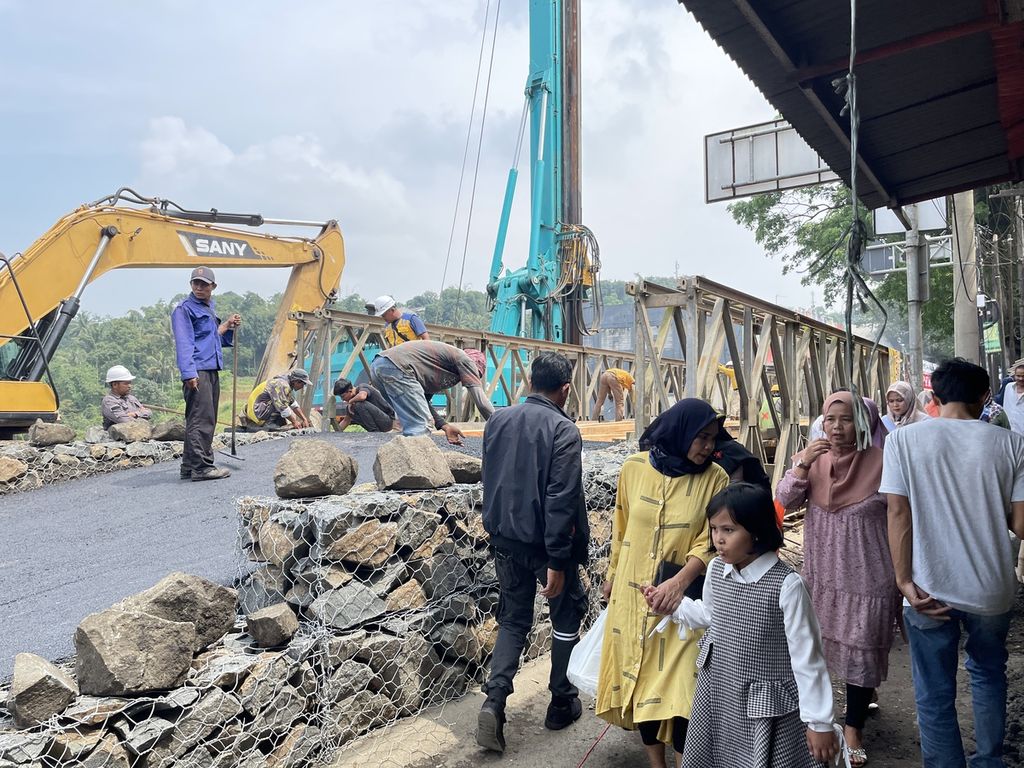 Celah antara jembatan dan ruko digunakan warga sebagai jalan untuk melintas setelah longsornya Jembatan Cikereteg di jalan nasional Ciawi-Benda, Kabupaten Bogor, Jawa Barat, yang longsor pada Senin (27/2/2023).