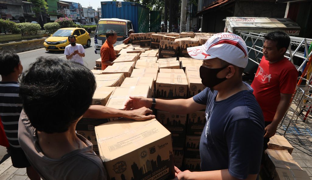 Warga menata kardus bantuan sosial Pemprov DKI yang diturunkan dari truk ekspedisi di Kelurahan Bidara Cina, Kecamatan Jatinegara, Jakarta Timur, akhir Juli 2020.  