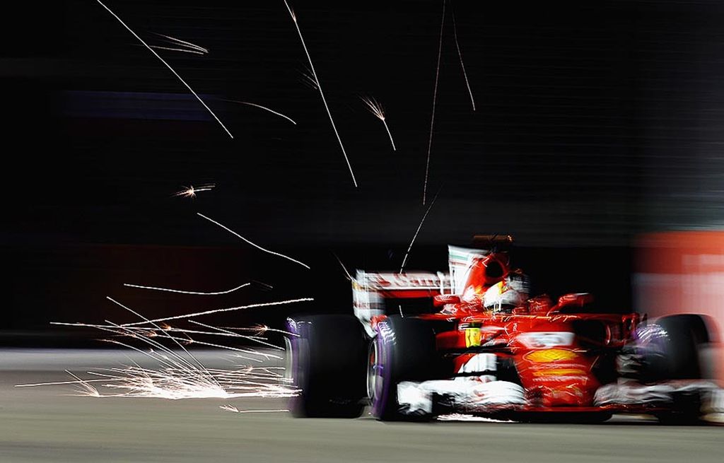 Percikan api menyala di belakang mobil Ferrari SF70H yang dipacu  Sebastian Vettel pada sesi kualifikasi Formula 1 seri Singapura di Sirkuit Marina Bay Street, Sabtu (16/9). Vettel meraih posisi start terdepan untuk balapan F1, Minggu ini pukul 19.00 WIB.