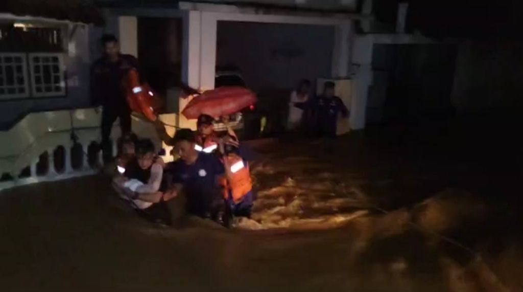 Petugas mengevakuasi warga yang terjebak banjir di dalam rumahnya, Sabtu (24/2/2024) malam. 