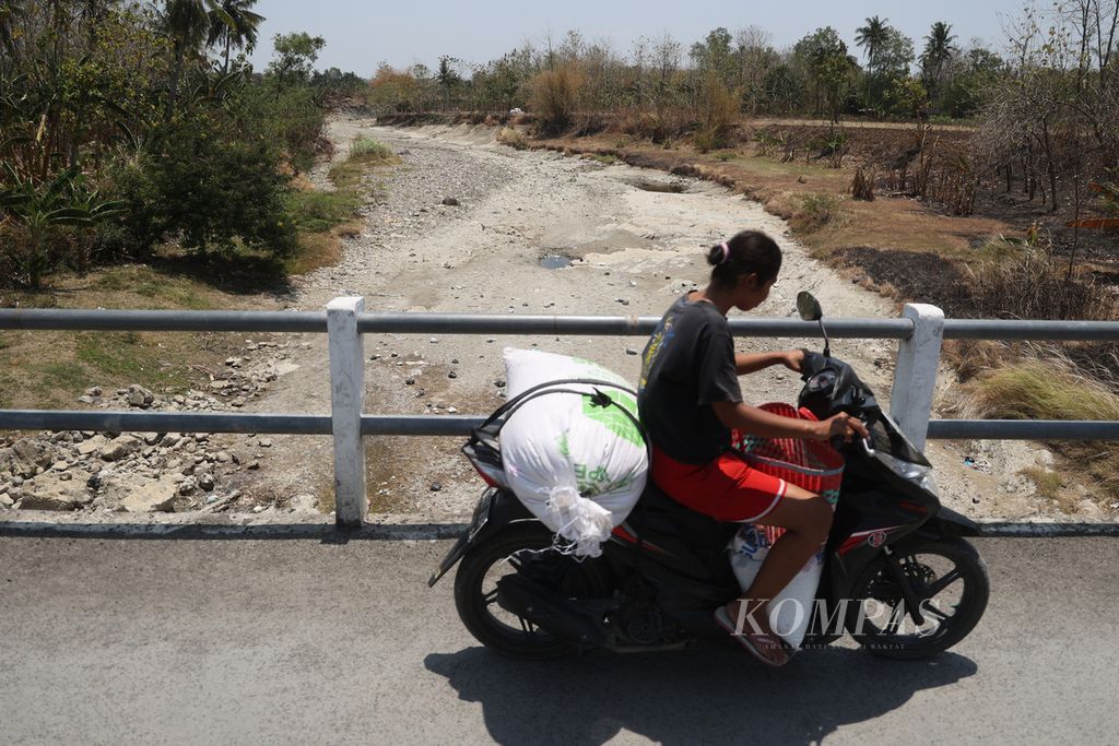Residents cross a bridge above the Repaking River in Repaking Village, Wonosamodro, Boyolali, Central Java, which has dried up due to the drought, on Tuesday (19/9/2023). The drought in Boyolali continues to expand and is being experienced by residents in ten districts in the regency.