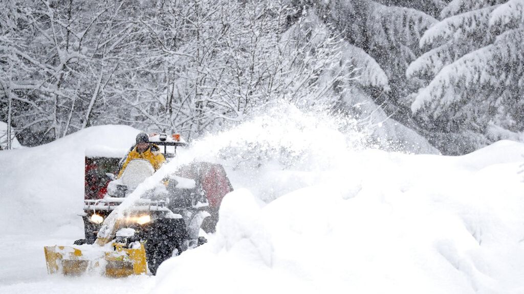 Warga membersihkan lahan parkir dari tumpukan salju setelah hujan salju lebat di Provinsi Tyrol, Austria, Kamis (28/1/2021). 