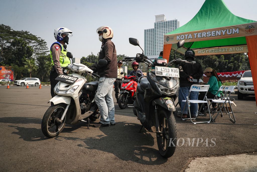 Polisi menegur pengendara sepeda motor yang tidak lulus uji emisi di Jalan Asia Afrika, Jakarta Pusat, Jumat (25/8/2023). 