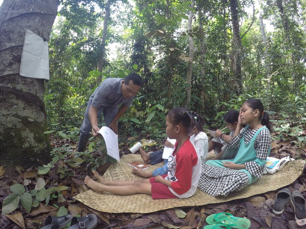 Teguh Rianto (37) membimbing siswa-siswanya belajar di wilayah Kelompang, Hutan Harapan, Kabupaten Batanghari, Jambi, Jumat (26/11/2021). Pendidikan adaptif terus didorong bagi warga yang hidup di pedalaman. Guru berperan penting di dalamnya.