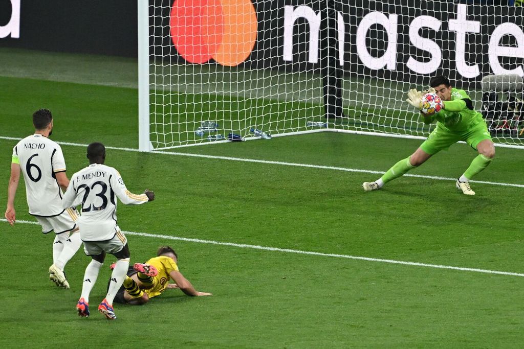 Kiper Real Madrid, Thibaut Courtois, menyelamatkan gawangnya dari ancaman striker Borussia Dortmund, Niclas Fuellkrug, pada laga final Liga Champions di Wembley, London, Minggu (2/6/2024) dini hari WIB. 