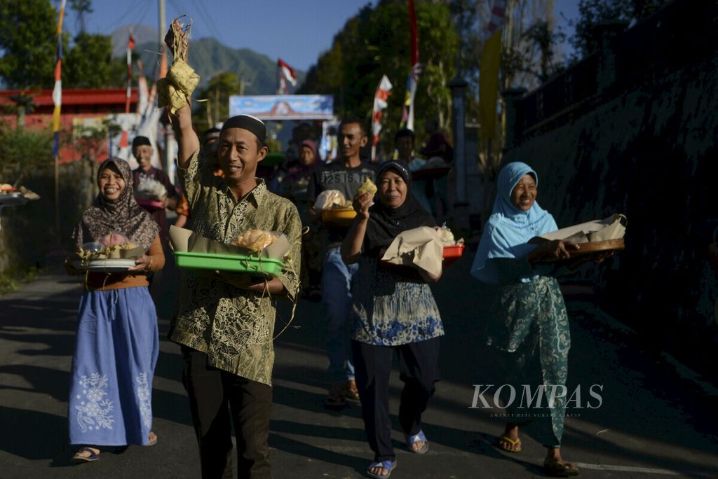 Warga membawa pulang hidangan dalam tradisi Syawalan di Dusun Mlambong,  Boyolali, Jawa Tengah, 12 Juni 2019. Tradisi itu digelar setiap tahun setelah hari raya Idul Fitri untuk mempererat silaturahmi antarwarga.