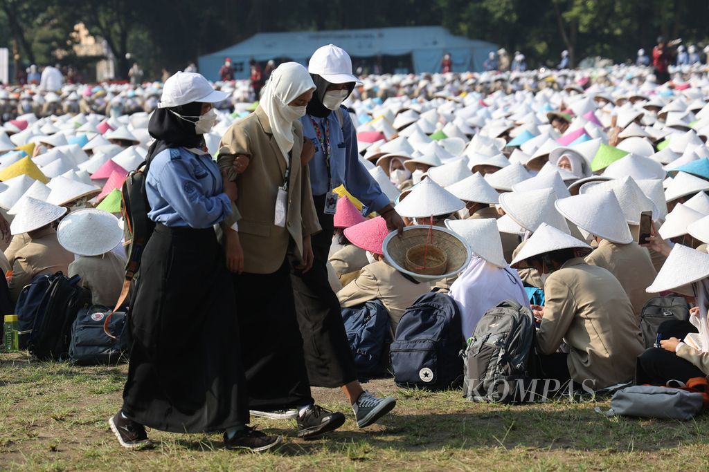 Mahasiswa baru yang dalam kondisi tidak sehat mendapat pendampingan dari kakak angkatan mereka saat mengikuti upacara penerimaan mahasiswa baru di Lapangan Pancasila UGM, Yogyakarta, Senin (1/8/2022). 