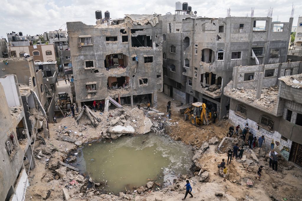 Sebuah lubang besar menganga akibat serangan udara oleh Israel di tengah hunian warga di Beit Hanoun, Jalur Gaza, Palestina, Minggu (23/5/2021). Kerusakan tersebut akibat gencatan senjata 11 hari antara Israel dan kelompok Hamas. 