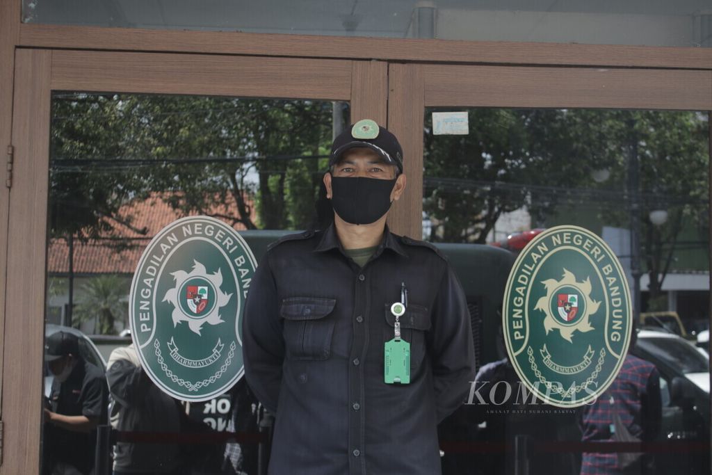 Petugas berjaga di depan pintu tempat persidangan terdakwa kekerasan seksual terhadap belasan anak di Kota Bandung, Herry Wirawan, di Pengadilan Negeri Bandung Kelas IA Khusus, Kota Bandung, Jawa Barat, 11 Januari 2022. 
