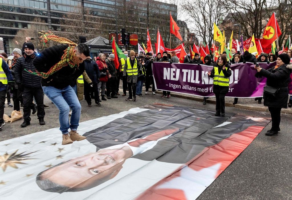 Seorang peserta unjuk rasa melompat di atas foto Presiden Turki Recep Tayyip Erdogan dalam demonstrasi yang digelar olrh Pusat Masyarakat Demokrat Kurdi guna menentang Erdogan dan langkah Swedia bergabung NATO di Stockholm, Swedia, 21 Januari 2023. 