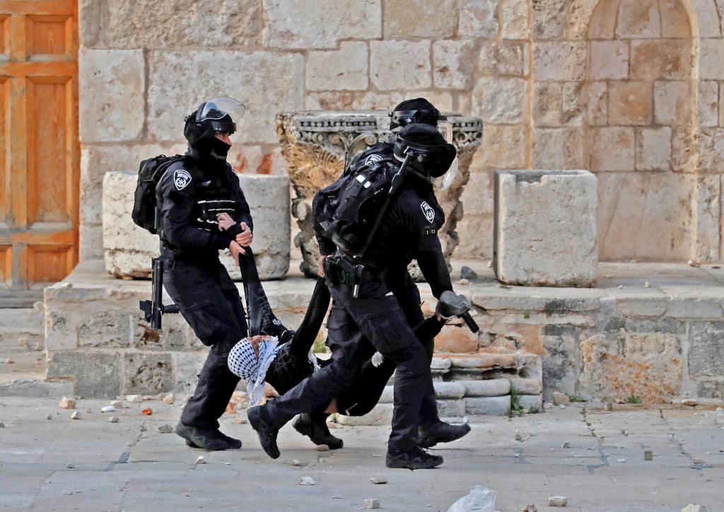 Tiga polisi Israel menahan seorang pemuda Palestina yang terlibat bentrok di Komplek Mesjid Al Aqsa, Jumat (22/4). Liga Arab mengecam tindakan aparat keamanan Israel yang mengizinkan warga Yahudi beribadah di Komplek Mesjid Al Aqsa sebagai tindakan yang provokatif dan ilegal. (Photo by Ahmad GHARABLI / AFP)