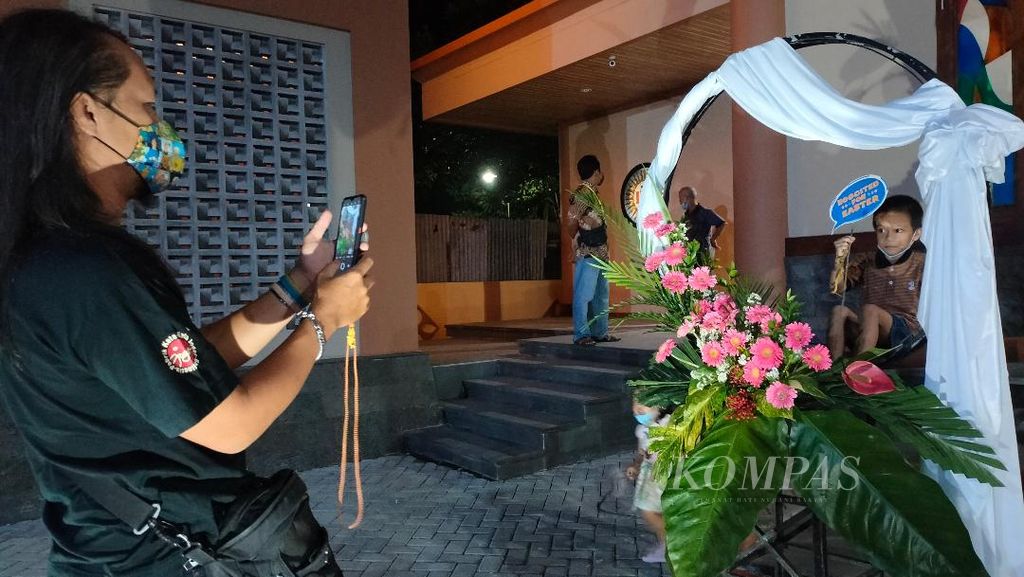 Seorang ayah memotret putranya yang bergaya di <i>photo booth</i> yang disediakan panitia perayaan Paskah di Gereja St Mikael, Kabupaten Magelang, Jawa Tengah, Sabtu (8/4/2023).