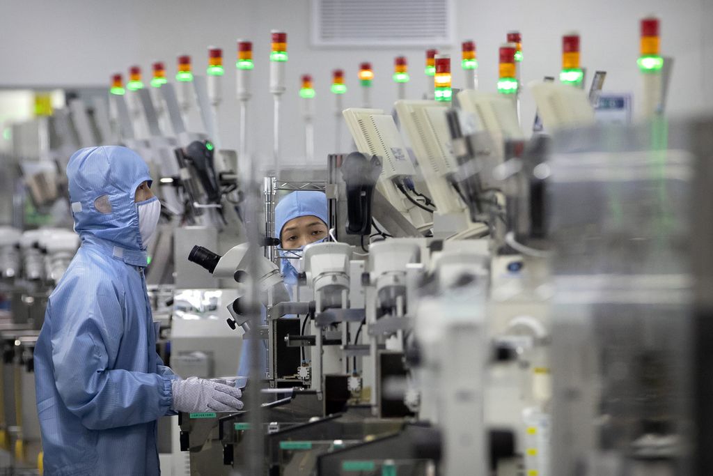 Foto yang diambil pada 14 Maret 2020 memperlihatkan seorang staf pabrik dengan mengenakan pakaian pelindung memeriksa proses pembuatan semikonduktor di Renesas Electronics di Beijing, China.  