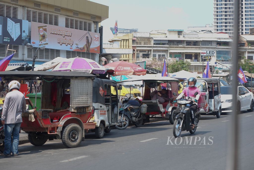 Deretan tuktuk tradisional Kamboja dan<i></i>tuktuk roda tiga diparkir di tepian jalan dekat pasar, di Kota Phnom Penh, Kamboja, Selasa (2/5/2023) siang, Tuktuk tradisional tidak sepopuler tuktuk bajai dari India. Maka dari itu, tuktuk tradisional lebih sering mencari penumpang di pusat-pusat keramaian