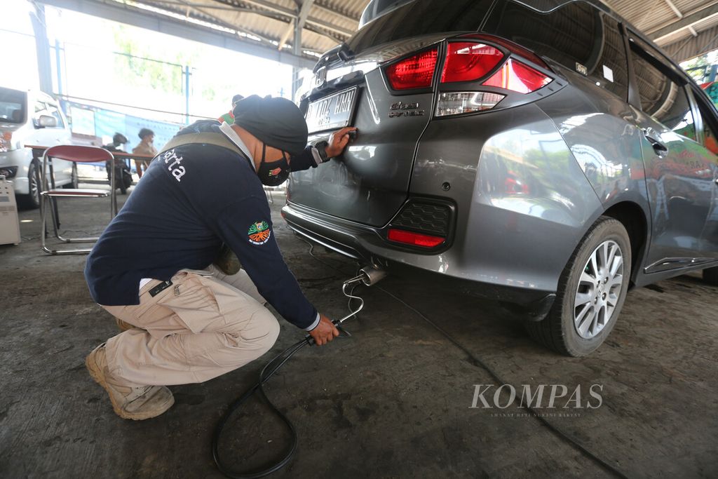 Petugas Dinas Lingkungan Hidup DKI Jakarta memasukkan alat penguji emisi ke knalpot kendaraan saat berlangsung uji emisi secara gratis di kompleks kantor di kawasan Cililitan, Jakarta, Selasa (2/11/2021). 