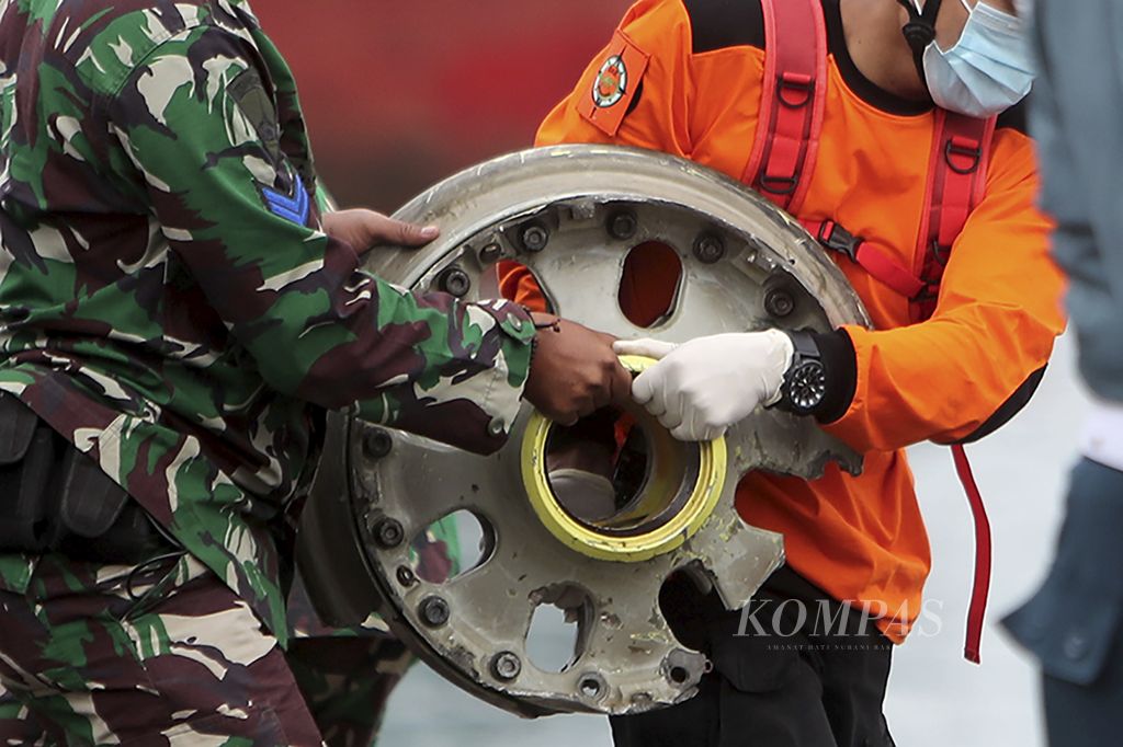 Petugas membawa bagian roda pesawat Sriwijaya Air SJ-182 PK-CLC yang jatuh di perairan Kepulauan Seribu, Jakarta Utara di Posko SAR Dermaga JICT, Pelabuhan Tanjung Priok, Jakarta, Minggu (10/1/2021).