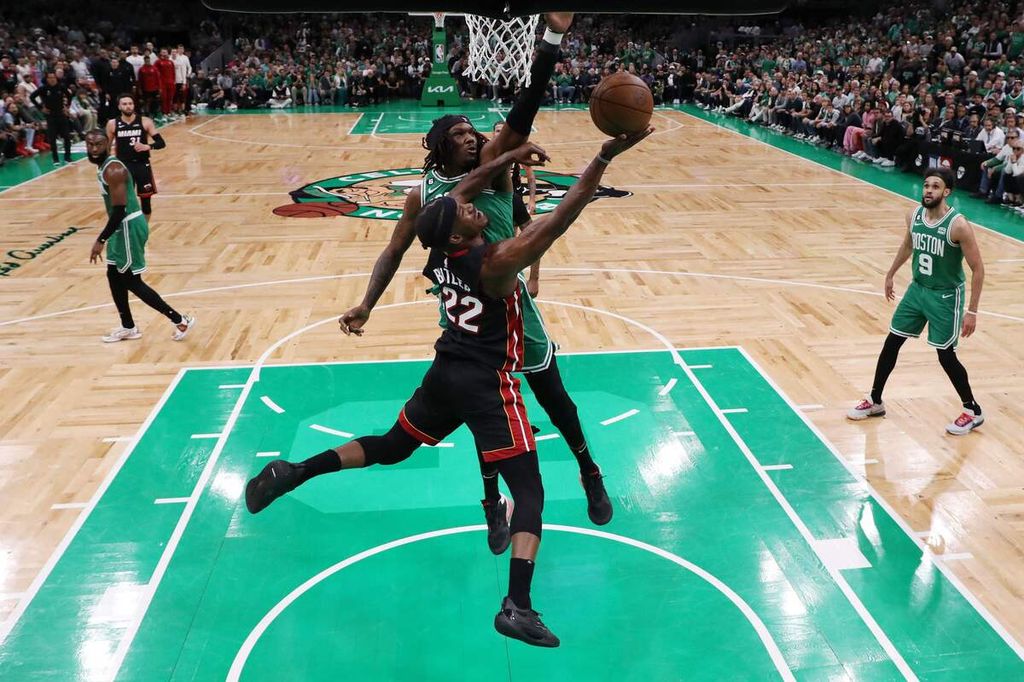 Bintang Miami Heat, Jimmy Butler (bawah), berupaya memasukkan bola ke keranjang tuan rumah Boston Celtics pada gim ketujuh final Wilayah Timur NBA di TD Garden, Boston, Amerika Serikat, Selasa (30/5/2023). Heat menang, 103-84, dan lolos ke final NBA dengan keunggulan 4-3 di final wilayah.