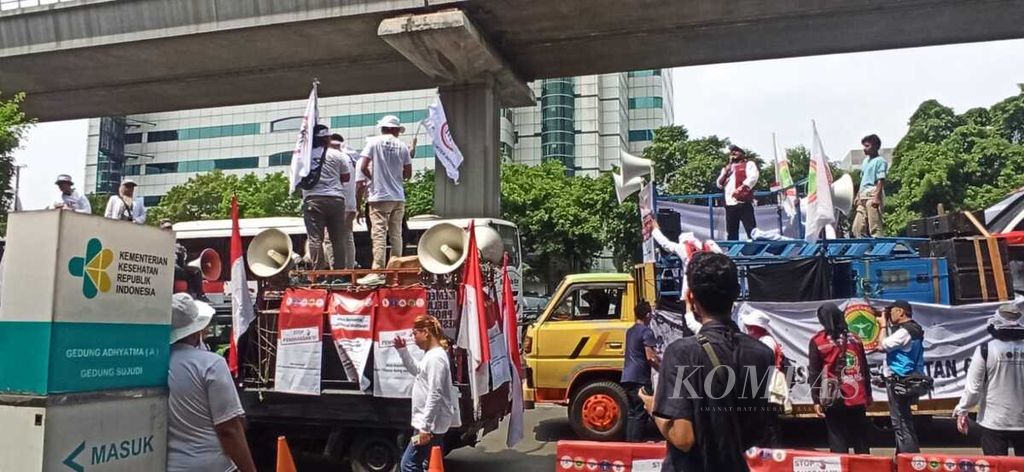 Sejumlah peserta aksi damai yang terdiri dari tenaga kesehatan dan tenaga medis mencoba menurunkan spanduk yang bertuliskan dukungan terhadap RUU Kesehatan yang dipasang di depan kantor Kementerian Kesehatan di Jakarta, Senin (8/5/2023). 