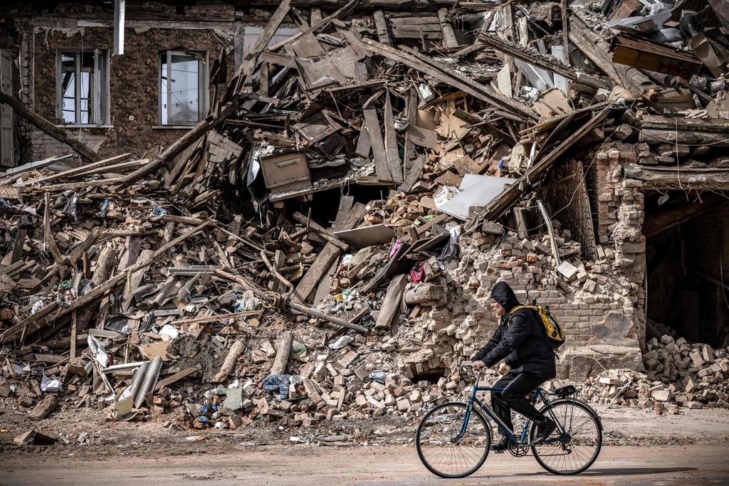 Pengendara sepeda melintas di depan reruntuhan bangunan di Kharkiv, Ukraina, Sabtu (2/4/2022). 