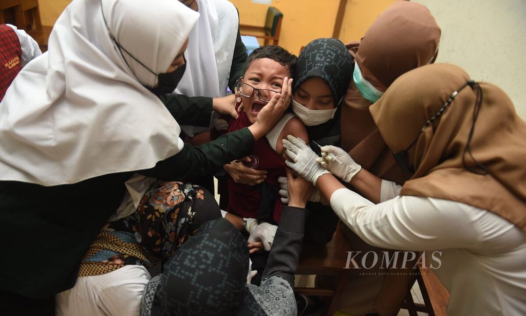 Siswa kelas I menangis saat mendapatkan vaksin <i>measles rubela</i> (MR) di Madrasah Ibtidaiyah Al Karim, Surabaya, Jawa Timur, Selasa (20/9/2022).