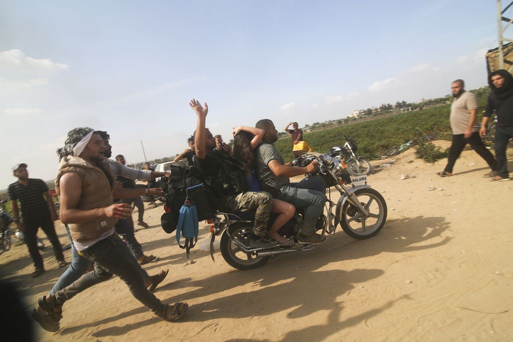 Warga Palestina mengangkut warga sipil Israel yang ditawan (tengah, naik sepeda motor) dari <i>kibbutz</i> Kfar Azza kibbutz ke Jalur Gaza, Sabtu (7/10/2023). 