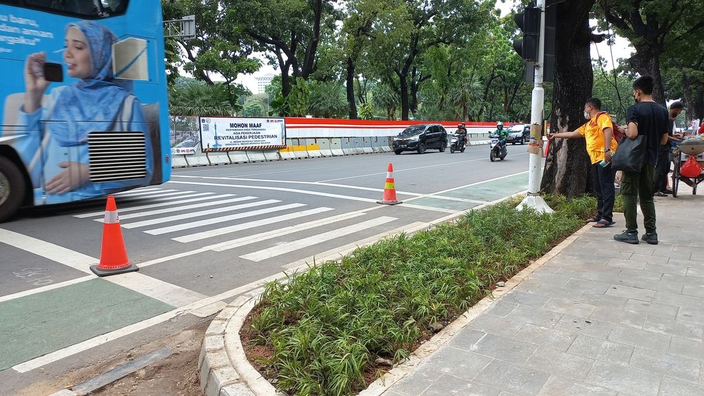 Pejalan kaki yang hendak menyeberang menggunakan <i>pelican crossing</i> di Jalan Medan Merdeka Selatan, Jakarta Pusat, Kamis (8/12/2022), harus menjangkau lebih jauh tiang tempat tombol pengatur lalu lintas berada. 