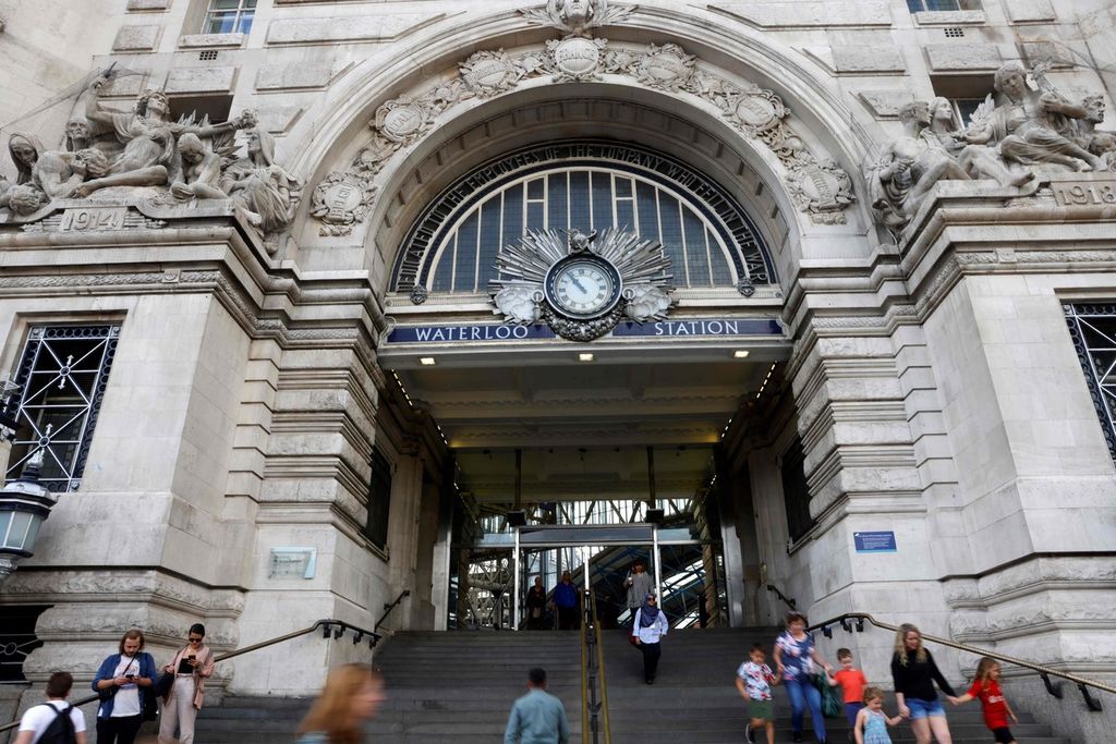 Warga berjalan keluar dan masuk melalui pintu gerbang utama Stasiun Waterloo, London, Inggris pada Kamis (18/8/2022).
