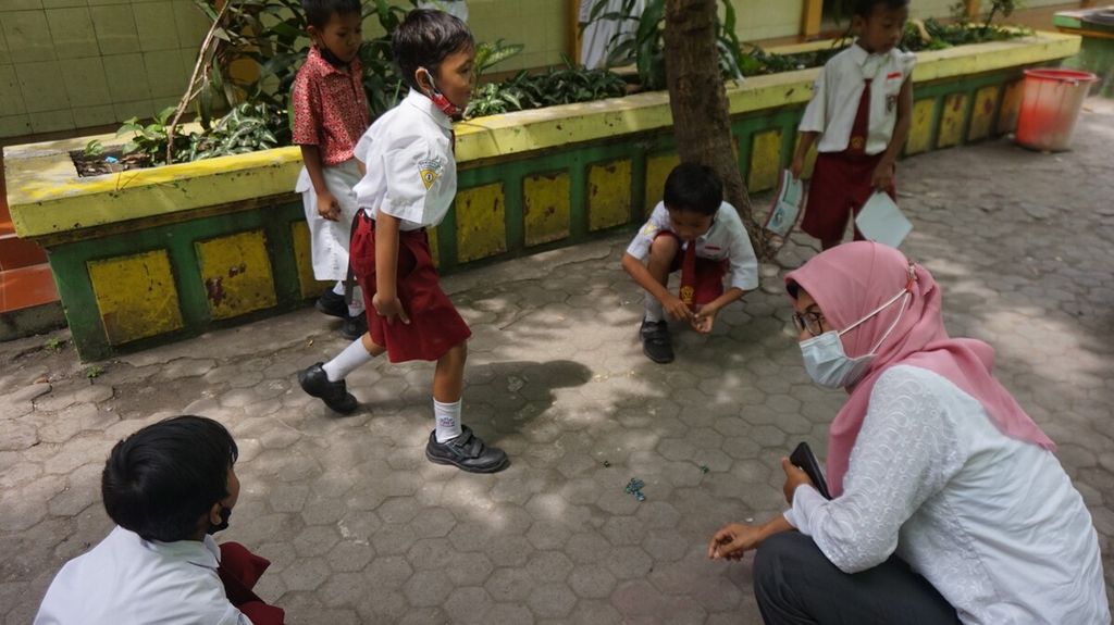 Guru mengajari sekaigus bermain kelereng bersama kalangan murid SD Negeri Mojo 3, Surabaya, Jawa Timur, Rabu (21/9/2022). 