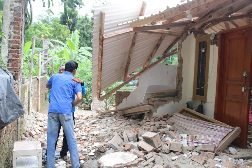 Salah satu warga saling menghibur di dekat rumahnya yang rusak berat di Kelurahan Cipameungpeuk, Kecamatan Sumedang Selatan, Sumedang, Jawa Barat, Senin (1/1/2024). Ratusan rumah mengalami kerusakan akibat gempa dangkal yang melanda Sumedang di pengujung 2023.