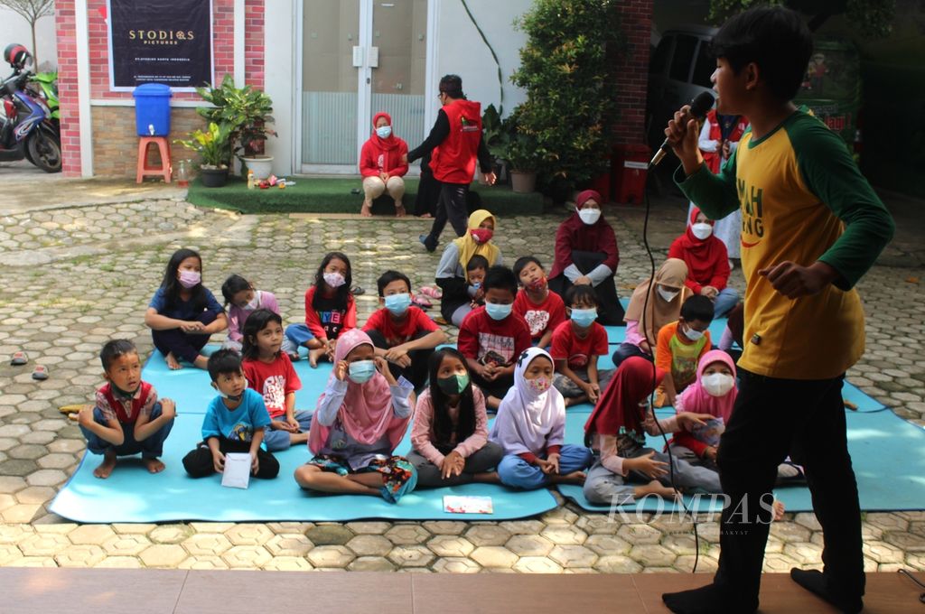 Sejumlah anak mendengarkan dongeng yang diceritakan oleh pendongeng dari Kampung Dongeng Indonesia, Natra (depan), di Ciputat, Tangerang Selatan, Banten, pada Hari Dongeng Sedunia, Minggu (20/3/2022).