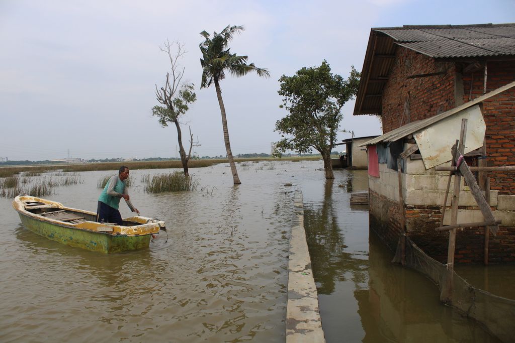 Salah satu warga menggunakan perahunya untuk melintasi area sawah yang terendam banjir di Desa Karangligar, Kecamatan Telukjambe Barat, Karawang, Jawa Barat, Senin (18/3/2024).
