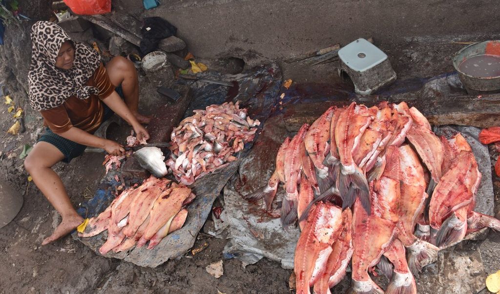 Warga memotong ikan patin untuk diasap di Jalan Kalimas Timur, Kota Surabaya, Jawa Timur, Rabu (23/2/2022). 
