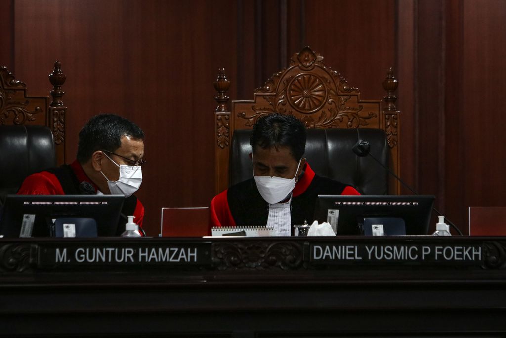 Hakim Konstitusi M Guntur Hamzah (kiri) berbincang dengan Hakim Konstitusi Daniel Yusmic Pancastaki Foekh (kanan) saat sidang putusan di Gedung MK, Jakarta, Rabu (30/11/2022).