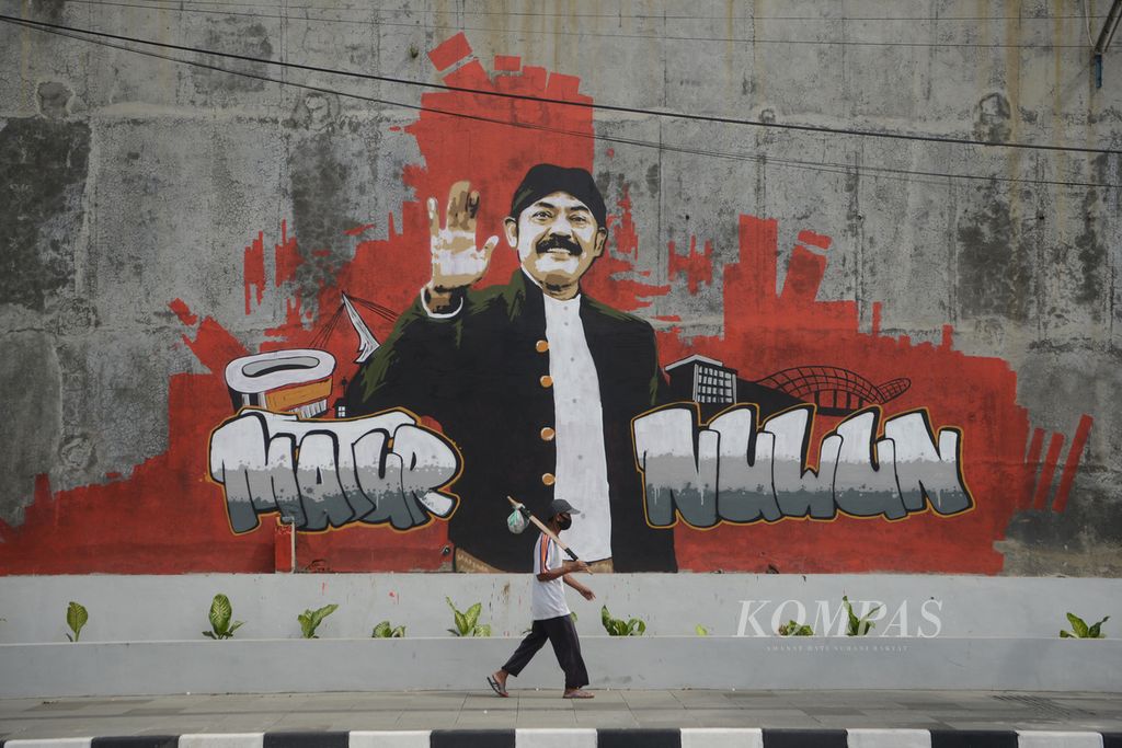 Pejalan kaki melintas di depan mural bergambar sosok mantan Wali Kota Surakarta FX Hadi Rudyatmo di Jalan Ir Juanda, Surakarta, Jawa Tengah, Sabtu (13/2/2021). 