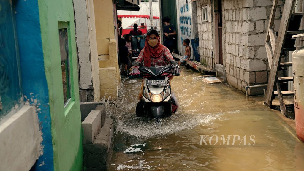 Warga menembus banjir rob di Blok Empang, Kelurahan Pluit, Penjaringan, Jakarta Utara, Kamis (6/1/2022). 