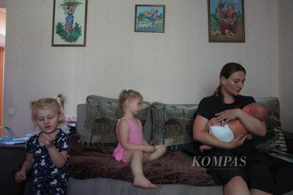 Tanya (29) menggendong Ilya, bayinya yang berusia 1 bulan, sambil mengasuh dua putrinya yang lain, Anya (4), tengah; dan Vika (2,5), paling kiri, di Zaporizhzhia, Ukraina, Selasa (21/6/2022). Tanya beserta tiga anaknya merupakan warga Mariupol yang terpaksa mengungsi ke Zaporizhzhia. Anya, Vika, dan Ilya kini menjadi yatim setelah suami Tanya tewas ditembak tentara Rusia. 