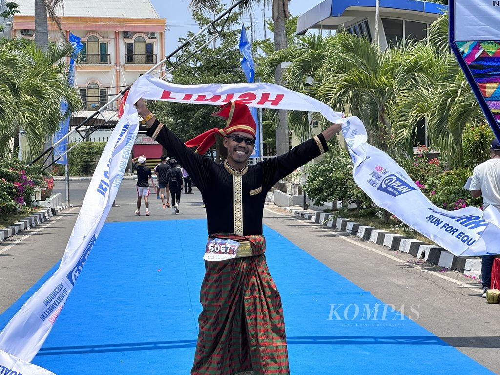 Tarman, pelari asal Makassar, mengenakan pakaian tradisional daerahnya saat finis di kategori 108k Jelajah Timur 2023 di Kota Kupang, Nusa Tenggara Timur, Sabtu (28/10/2023). Jelajah Timur 2023 adalah lari amal ultramaraton yang digelar Plan Indonesia untuk pemenuhan akses air bersih dan pencegahan tengkes di NTT. 