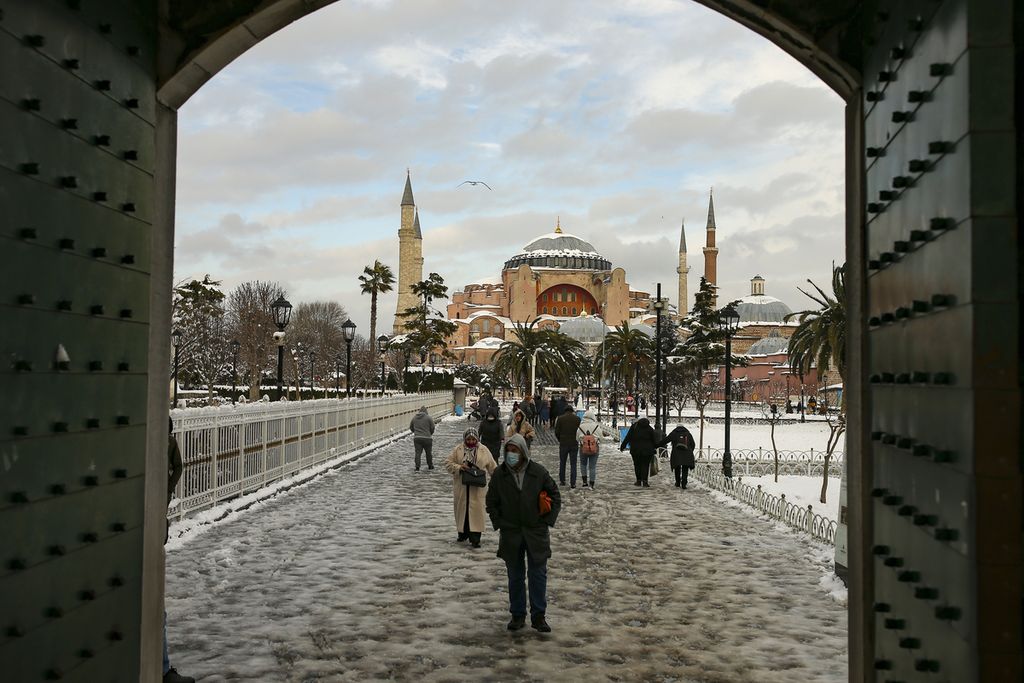 Pemandangan salah satu sudut taman yang berselubung salju di kota Istanbul, Turki, 25 Januari 2022, dengan latar belakang bangunan ikonik era Bizantium, Haghia Sophia. Sebelum dikenal dengan nama Istanbul, kota itu lebih dulu dikenal sebagai Bizantium, lalu Konstantinopel. Beberapa pemerintahan memilih kota itu sebagai pusat kekuasaannya. 