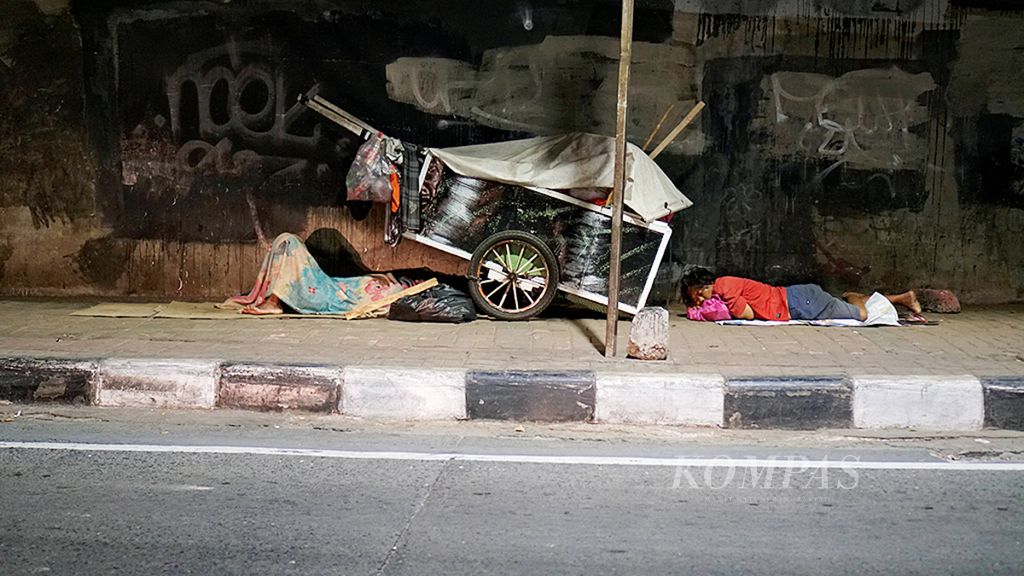 Tunawisma terlelap dekat gerobaknya di kolong tol dalam kota di Pejompongan, Jakarta Pusat, Kamis (14/12/2017)