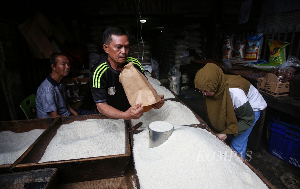 Pedagang melayani pembeli di toko beras di pasar Kebayoran Lama, Jakarta Selatan, Selasa (13/2/2024).