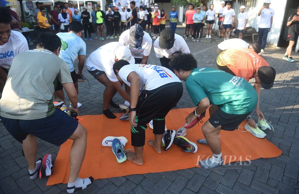 Peserta Run The Ground berebut memakai sepatu di Carrot Coffe, Surabaya, Sabtu (30/3/2024). 