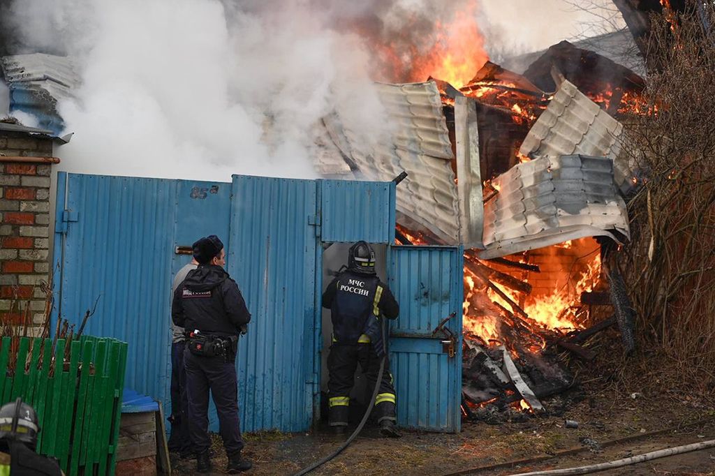Petugas tanggap darurat berupaya memadamkan api kebakaran yang melahap sebuah rumah setelah dihantam tembakan artileri di wilayah Belgorod, Rusia, Minggu (17/3/2024). 